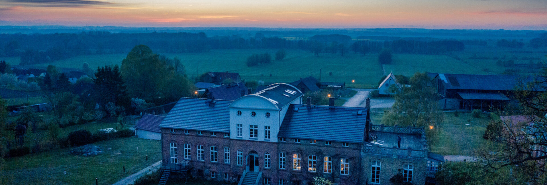 Gut Pohnstorf in der Abenddämmerung mit beleuchtetem Gutshaus