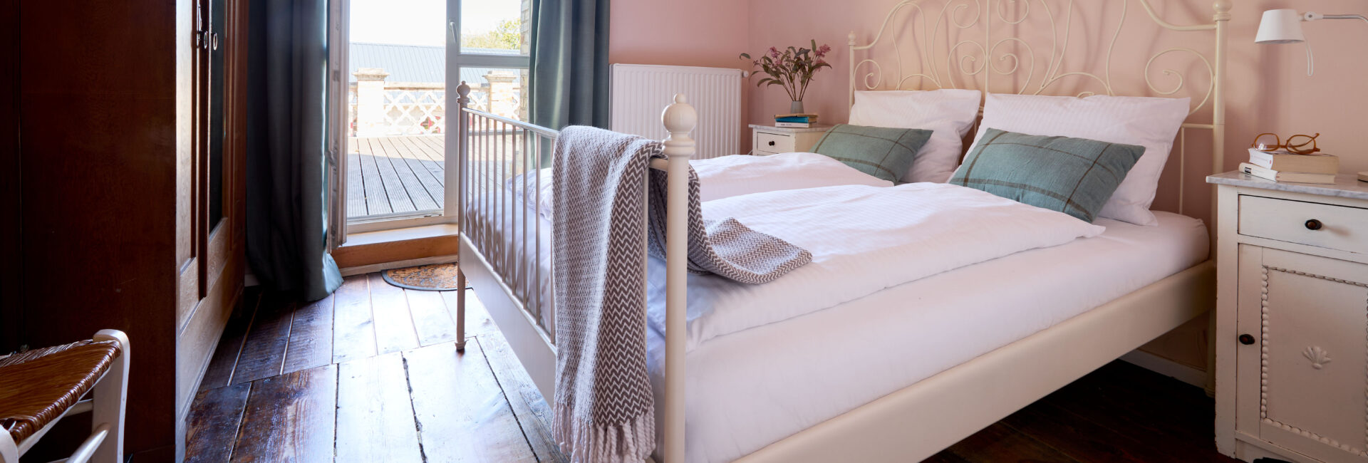 Schlafzimmer mit Doppelbett und Zugang zur Terrasse in der Wohnung Marie Gut Pohnstorf/Andrea Girard