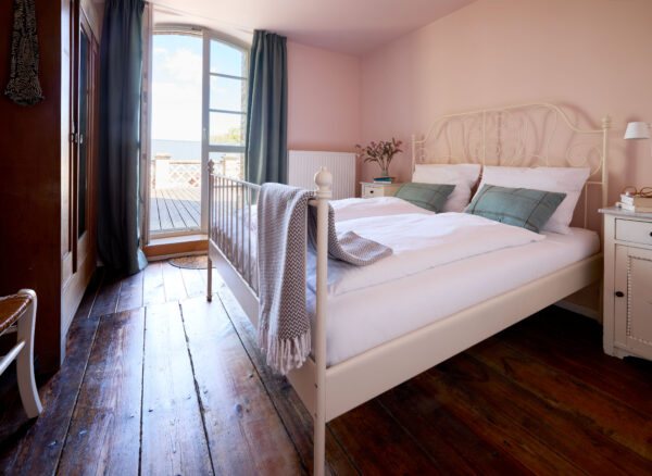 Schlafzimmer mit Doppelbett und Zugang zur Terrasse in der Wohnung Marie Gut Pohnstorf/Andrea Girard
